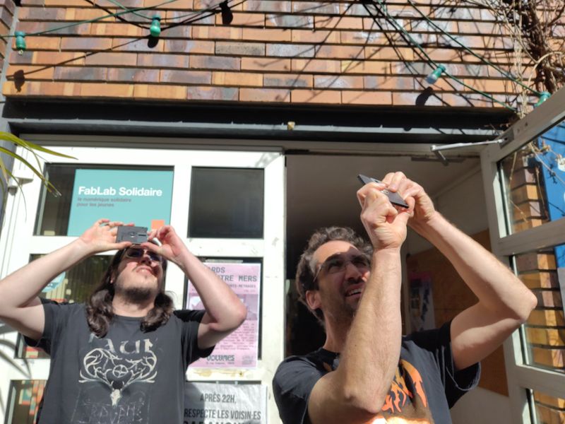 ewen et kask regardant l'éclipse partielle de soleil à travers une disquette